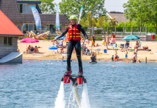 Persoon met wetsuit en reddingsvest doet aan flyboarden op Camping Betuwestrand in Nederland.