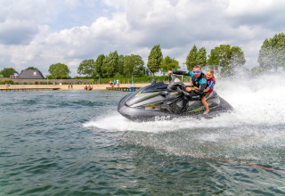 Zwei Personen fahren Jetski am Camping Betuwestrand, einem Ferienpark in Gelderland, Niederlande.