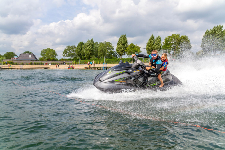 Twee personen varen op een jetski bij Camping Betuwestrand, een vakantiepark in Gelderland, Nederland.