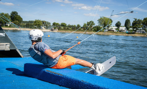 Persona con casco y wakeboard preparándose para deportes acuáticos en Camping Betuwestrand, Gelderland.