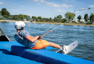Persoon met helm en wakeboard maakt zich klaar aan het water bij Camping Betuwestrand, Gelderland.