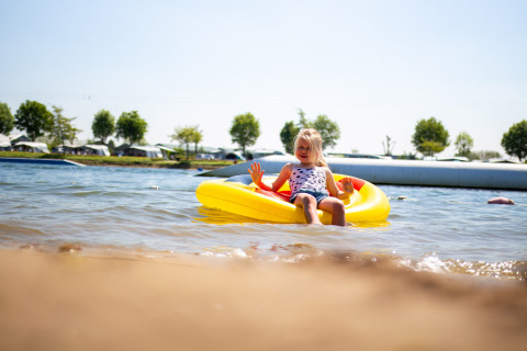 Una niña se relaja en una balsa inflable amarilla en el agua en Camping Betuwestrand, Gelderland, Países Bajos.