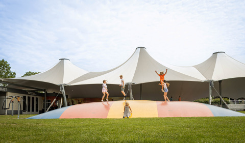 Niños jugando en una colorida almohada de salto en Camping Betuwestrand, parque vacacional en Gelderland, Países Bajos.