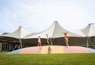 Kinder spielen auf einem bunten Hüpfkissen im Camping Betuwestrand, Ferienpark in Gelderland, Niederlande.