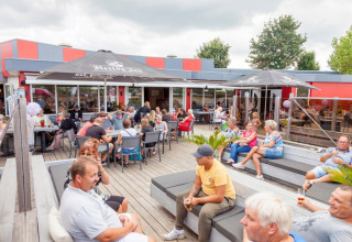 Vakantiegangers ontspannen op het terras van Camping Betuwestrand in Gelderland, Nederland, bij mooi weer.
