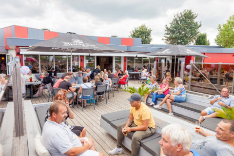 Villeggianti al Camping Betuwestrand in Gheldria, Paesi Bassi, si rilassano sulla terrazza esterna.
