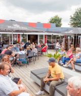 Holidaymakers at Camping Betuwestrand in Gelderland, Netherlands, relax on the lively outdoor terrace.
