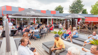 Turistas en Camping Betuwestrand en Gelderland, Países Bajos, disfrutan de la terraza al aire libre.
