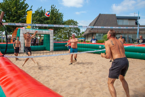 Gæster spiller beachvolleyball på sandet ved Camping Betuwestrand i Gelderland, Holland, på en solrig dag.