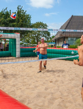 Guests enjoy a sunny day playing beach volleyball at Camping Betuwestrand holiday park in Gelderland, Netherlands.