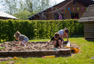 Kinderen spelen in een zandbak op Camping Betuwestrand, een vakantiepark in Gelderland, Nederland.