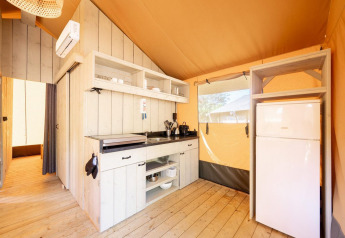 Interior de una tienda safari Villatent Nomad con cocina y nevera en Holiday Park Ackersate, Países Bajos.