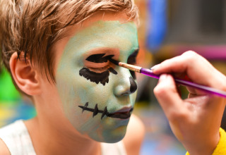 Et barn får ansigtsmaling i monsterstil, en populær aktivitet på Camping Borken am See i Tyskland.