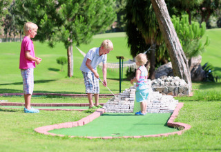 Tre børn spiller minigolf udendørs på Camping Borken am See i Nordrhein-Westfalen, Tyskland.