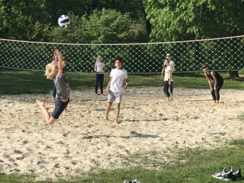 Niños y adultos juegan voleibol de playa en una cancha de arena en Camping Borken am See, Alemania.