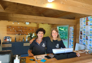 Zwei Frauen stehen an der Rezeption von Camping Borken am See in einer Holzhütte in Nordrhein-Westfalen.