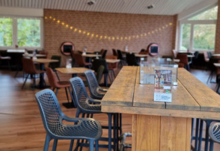 Modern dining area at Camping Borken am See with wooden table, bar stools, and cozy lighting in Germany.