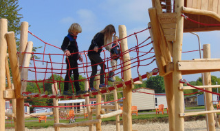 Niños juegan sobre un puente de cuerdas en el parque infantil de Camping Borken am See, Alemania.