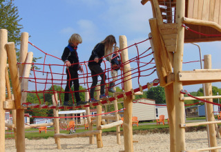 Children playing on a wooden and rope climbing playground at Camping Borken am See holiday park in Germany.