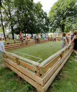 Niños y adultos disfrutan en un campo de fútbol pequeño en el Camping Borken am See en Alemania.