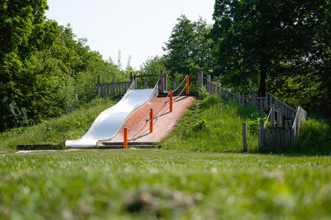 Spielplatz mit einer Rutsche und Treppe im Grünen im Ferienpark Camping Borken am See, Nordrhein-Westfalen.