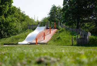 Spielplatz mit einer Rutsche und Treppe im Grünen im Ferienpark Camping Borken am See, Nordrhein-Westfalen.