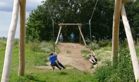 Niños jugando en una tirolina al aire libre en Camping Borken am See, un parque vacacional en Renania del Norte-Westfalia.