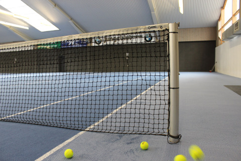 Campo da tennis al coperto con rete e palline a terra al Camping Borken am See, Germania.