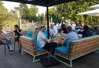 Outdoor dining scene at Camping Borken am See with people enjoying food and drinks in the sunshine.