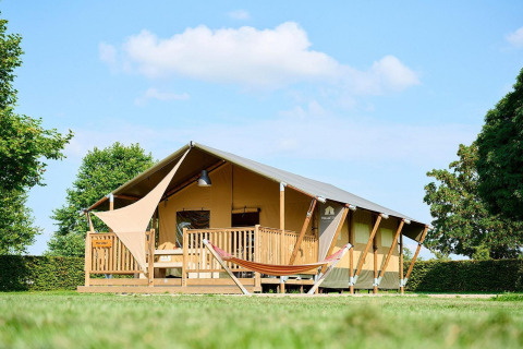 Tienda safari Villatent Nomad en Camping Betuwe, Países Bajos, con porche y hamaca en un entorno verde.