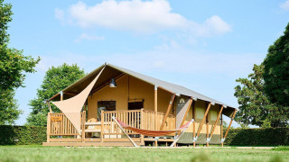 Safaritent Villatent Nomad op Camping Betuwe in Nederland met houten veranda en hangmat in het groen.