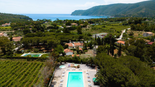 Vista aerea di Camping Casa dei Prati in Toscana, Italia, con piscina, aree verdi e vista mare sullo sfondo.