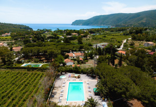 Luchtfoto van Camping Casa dei Prati in Toscane, Italië, met zwembad, groene omgeving en uitzicht op zee.