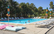 Piscina all'aperto con lettini e ombrelloni colorati al Camping Casa dei Prati in Toscana, Italia.