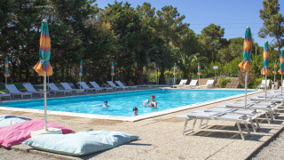 Piscina al aire libre con tumbonas y coloridas sombrillas en Camping Casa dei Prati en la Toscana, Italia.