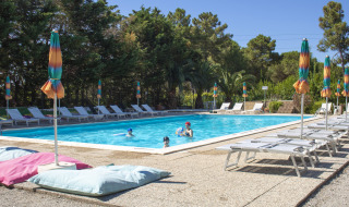 Piscina al aire libre con tumbonas y coloridas sombrillas en Camping Casa dei Prati en la Toscana, Italia.