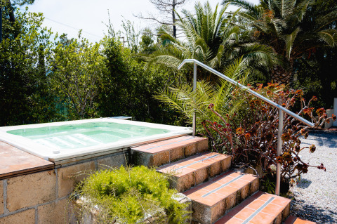 Jacuzzi exterior en Camping Casa dei Prati, Toscana, Italia, rodeado de palmeras y vegetación exuberante.