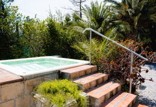 Bain à remous extérieur au Camping Casa dei Prati en Toscane, Italie, entouré de palmiers et verdure luxuriante.