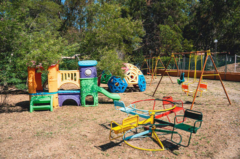 Parco giochi con altalene, scivolo e giostra a Camping Casa dei Prati, parco vacanze in Toscana, Italia.