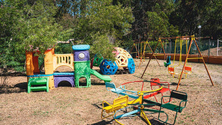 Parque infantil con columpios, tobogán y tiovivo en Camping Casa dei Prati, Toscana, Italia.