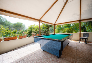 Mesa de billar exterior bajo toldo con vistas a la vegetación en Camping Casa dei Prati, Toscana, Italia.