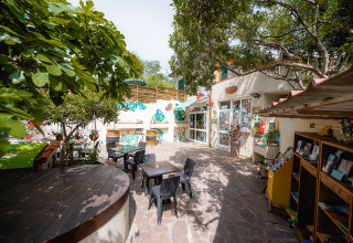 Accogliente patio esterno con tavoli, sedie e alberi verdi al Camping Casa dei Prati in Toscana, Italia.