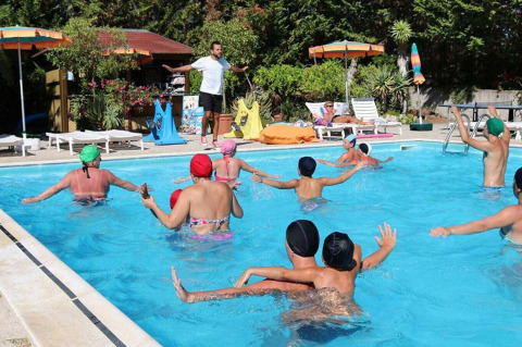 Personas participan en una clase de aquaeróbic en la piscina de Camping Casa dei Prati, un parque vacacional en la Toscana, Italia.