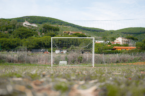 Ein Fußballtor auf einer Wiese vor grünen Hügeln und Gebäuden im Camping Casa dei Prati, Toskana, Italien.