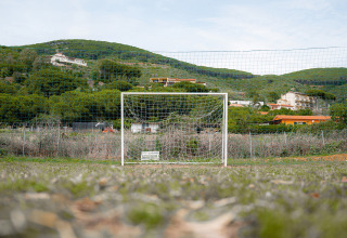 Ein Fußballtor auf einer Wiese vor grünen Hügeln und Gebäuden im Camping Casa dei Prati, Toskana, Italien.