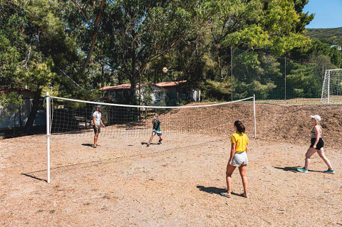 Huéspedes juegan al voleibol en una cancha exterior rodeada de árboles en Camping Casa dei Prati, Toscana, Italia.