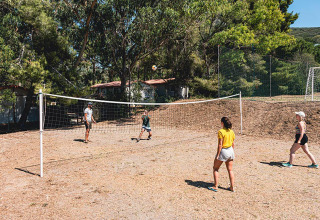 Gasten spelen volleybal op het buitenterrein van Camping Casa dei Prati, omringd door bomen in Toscane.