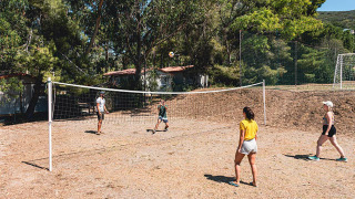 Huéspedes juegan al voleibol en una cancha exterior rodeada de árboles en Camping Casa dei Prati, Toscana, Italia.