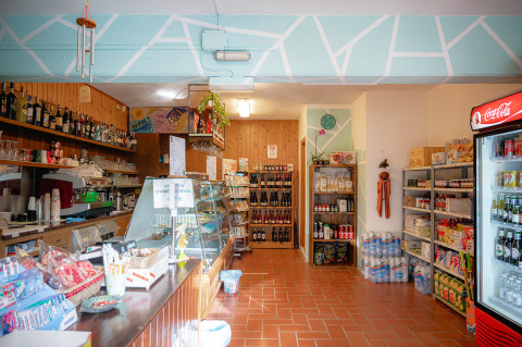 Area negozio accogliente con prodotti locali, bevande e angolo bar al Camping Casa dei Prati, Toscana.