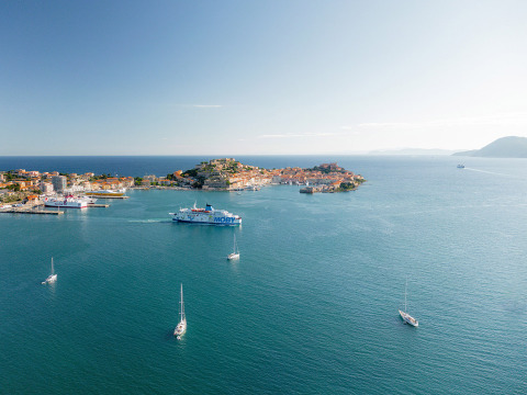 Aerial view of Camping Casa dei Prati, sailboats and colorful island scenery in Tuscany, Italy.